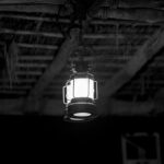 A small, dimly lit hanging light fixture in a darkly lit room