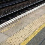 A train station platform with a sign that reads Mind the gap in yellow
